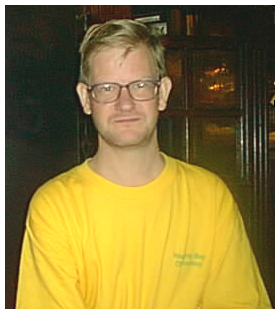 John Schmitt, smiling slightly, wearing glasses and a yellow T-shirt